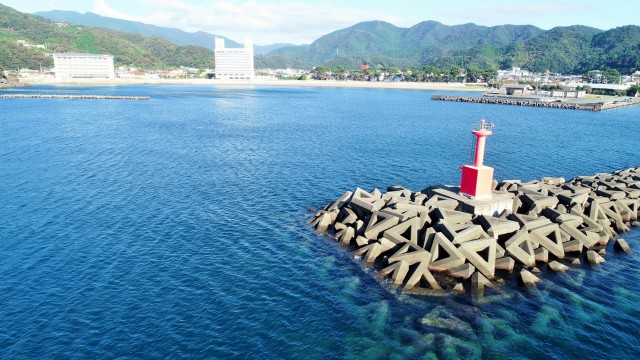 沖合にはシンボルでもある赤い灯台がある＝松崎町の松崎海岸