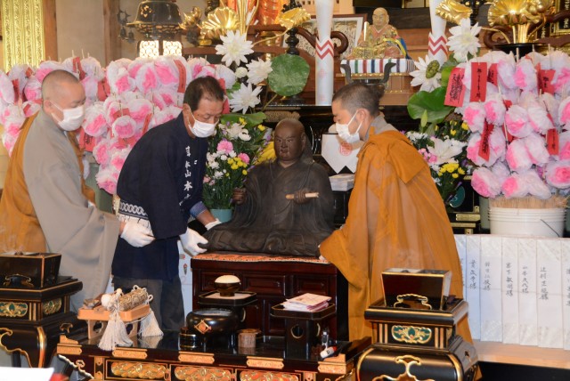 祖師像遷座開眼式で修復した「日蓮聖人御尊像」を元の場所に運ぶ僧侶ら＝伊豆の国市金谷の本立寺（１２日）