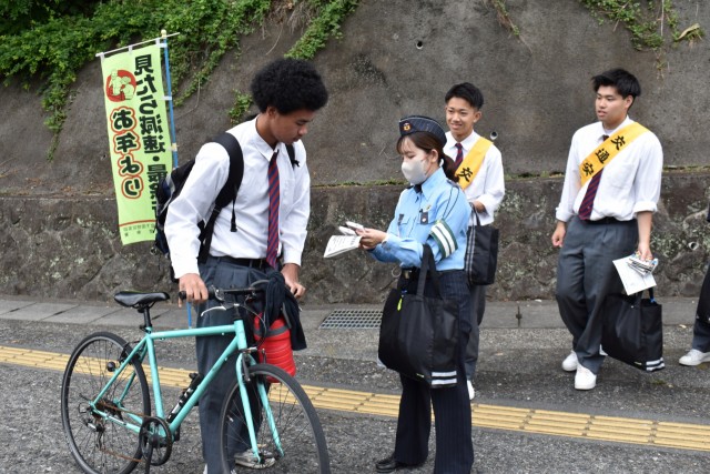 自転車で通学する生徒にヘルメット着用などを呼び掛ける参加者＝松崎町の松崎高前