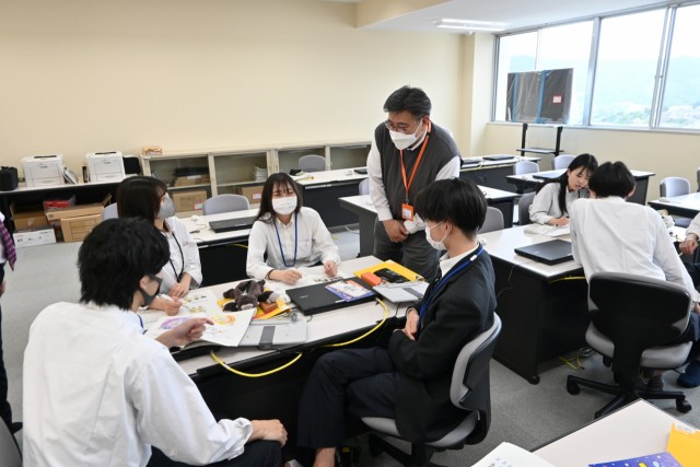 小野さん（右から３人目）を交え、脱炭素の視点も取り入れたビジネスプラン案を相談する生徒＝伊豆伊東