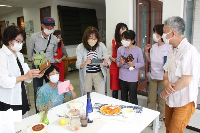 古根村さん（中央）からスマートフォンを使った撮影のこつを学ぶ参加者＝伊豆の国市の「ｉｎｃｏ」