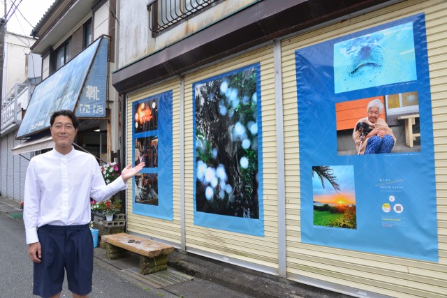 商店街のシャッターに特製ポスターを貼り出したあじさいＰＨＯＴＯストリートを紹介する青木さん＝下田市二丁目