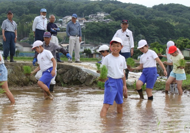 田植えの準備をする伊豆市の熊坂小の児童を見守る地域の人たち＝同市熊坂（６日）
