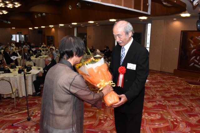 花束を受け取る佐藤さん（右）＝伊豆の国市のホテルサンバレー富士見