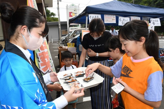 アイランドルビーの試食メニューを紹介する伊豆伊東高の生徒（左）＝伊東市玖須美元和田のいで湯っこ市場