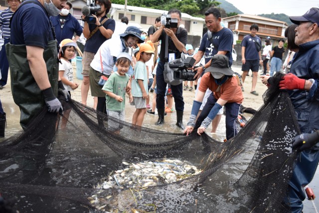 網に掛かった魚に喜ぶ園児たち＝松崎町の岩地海岸