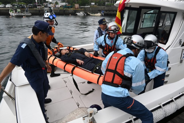 海で救助した水難者を救急隊員に引き渡す訓練参加者たち＝熱海市の熱海港