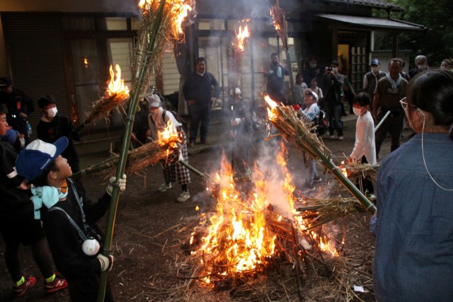 浅間神社例祭の「むしおくり行事」のため麦わらの燃える火をたいまつに移す子どもら＝伊豆の国市宗光寺の白幡神社（２４日）