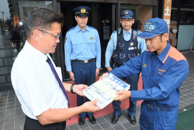 警察、消防関係者から水難事故防止のための広報紙を受け取る野毛理事長（左）＝伊豆市土肥