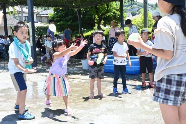 「松川タライ乗り競走」に合わせて開かれた「アイ・トゥ・マルシェ」で水風船を楽しむ子ども＝伊東市渚町の松川藤の広場（２日）