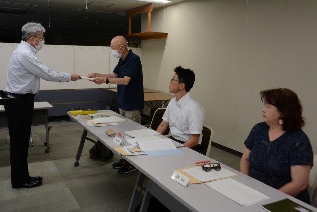 新村茂昭教育長（左）から委嘱状を受け取る委員＝熱海市立図書館