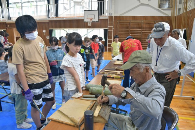 住民と一緒に竹を割りスプーンを作る児童たち＝伊東市の池小