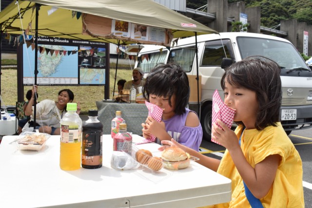出店の食べ物をおいしそうに頬張る子どもたち＝西伊豆町宇久須の黄金崎クリスタルパーク