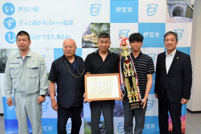 菊地市長（右）にグランドチャンピオン大会優勝を報告した堀江代表（左から２人目）ら天城連峰太鼓のメンバー＝伊豆市役所