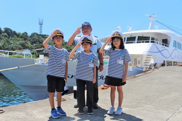 一日船長を終え、就航船の前でポーズを決める「小学生船長」ら＝熱海市初島（１６日）