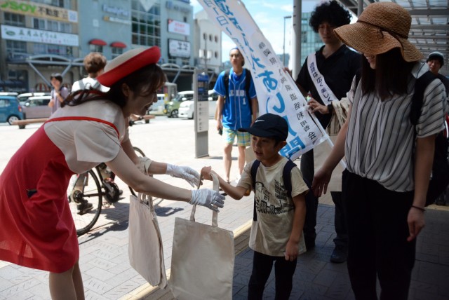 道の日の街頭キャンペーンで啓発品を受け取る子ども＝熱海市のＪＲ熱海駅前（２日）
