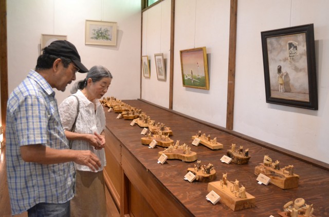来館者に作品を説明する中村さん（左）＝伊東市八幡野のりんがふらんか城ケ崎文化資料館