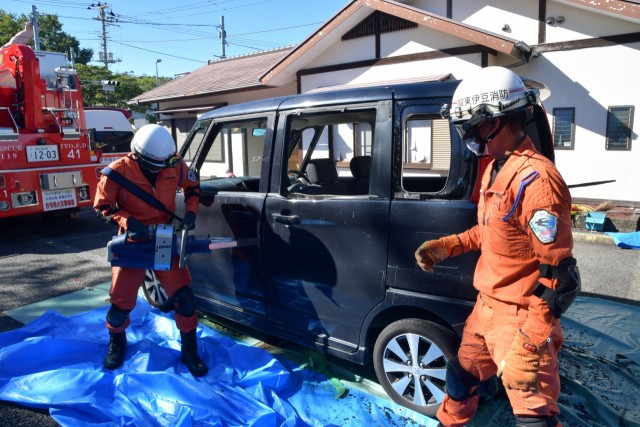 はさみ状の救助器具で自動車のドアをこじ開ける消防隊員＝伊東市富戸