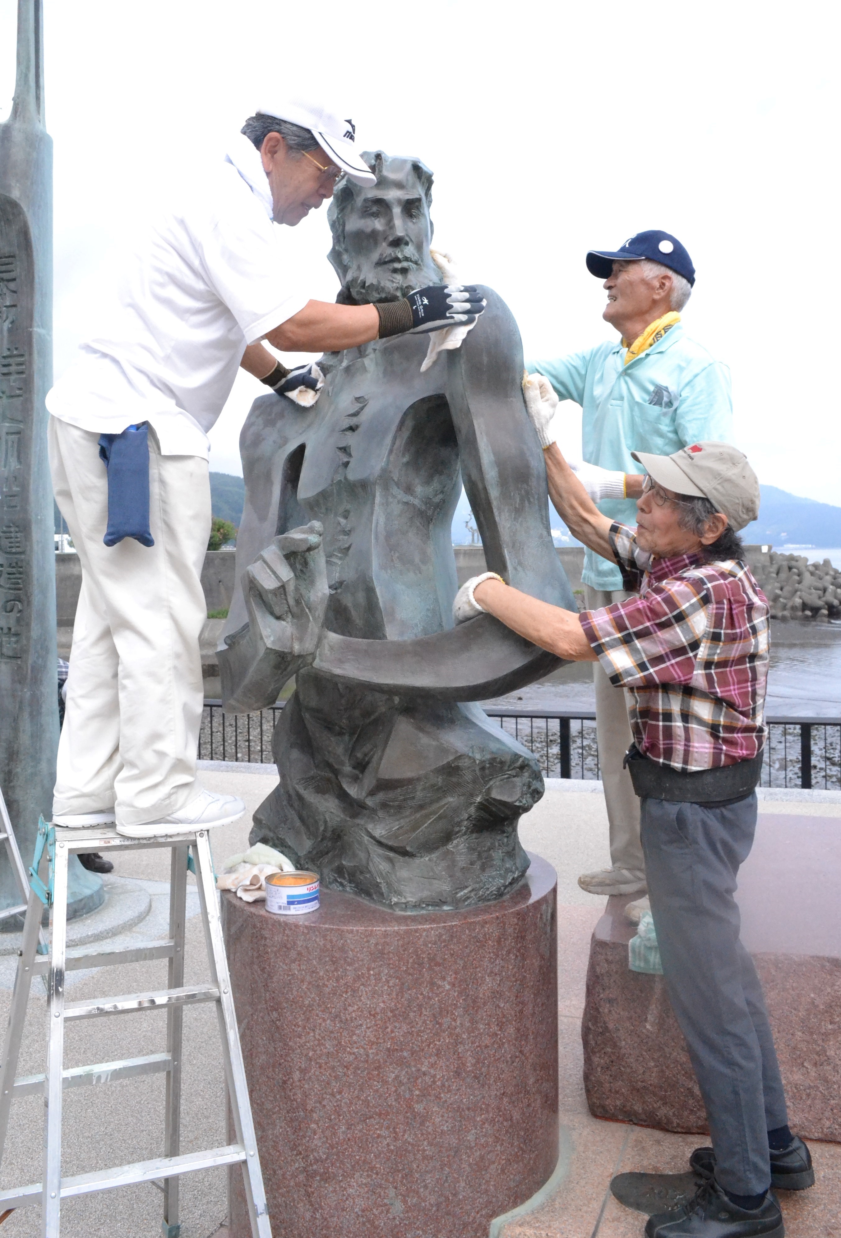 重岡さん（右）と一緒にアダムス像を清掃する参加者＝伊東市渚町の按針メモリアルパーク