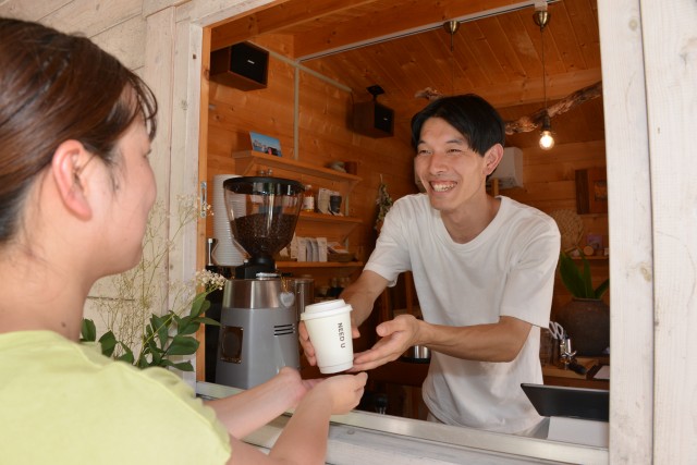看板商品の一つであるコーヒーを利用者に笑顔で手渡す板橋さん＝下田市吉佐美のニードユー