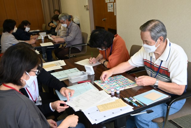 サポーター（左側）と協力して、すうじ盤や計算に取り組む参加者＝伊東市和田の市観光会館