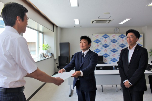 斉藤市長（左）に１０周年記念式典の招待状を手渡す鈴木会長（中央）＝熱海市役所