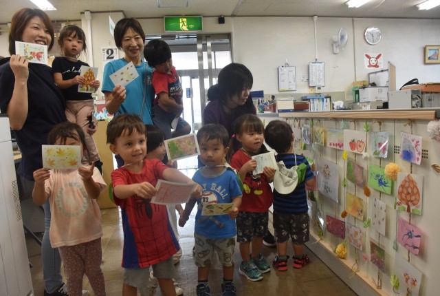 自分たちの作品が載ったポストカードを手にして笑顔を見せる園児たち＝三島市社会福祉会館