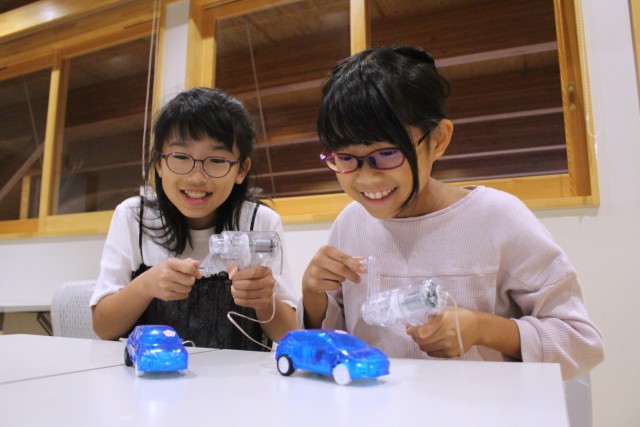 手回し式発電機でモデルカーに電力をためる子どもたち熱海市伊豆山の姫の沢公園