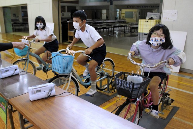 自転車をこいで発電に挑戦する児童＝熱海市の多賀小（写真の一部を加工しました）