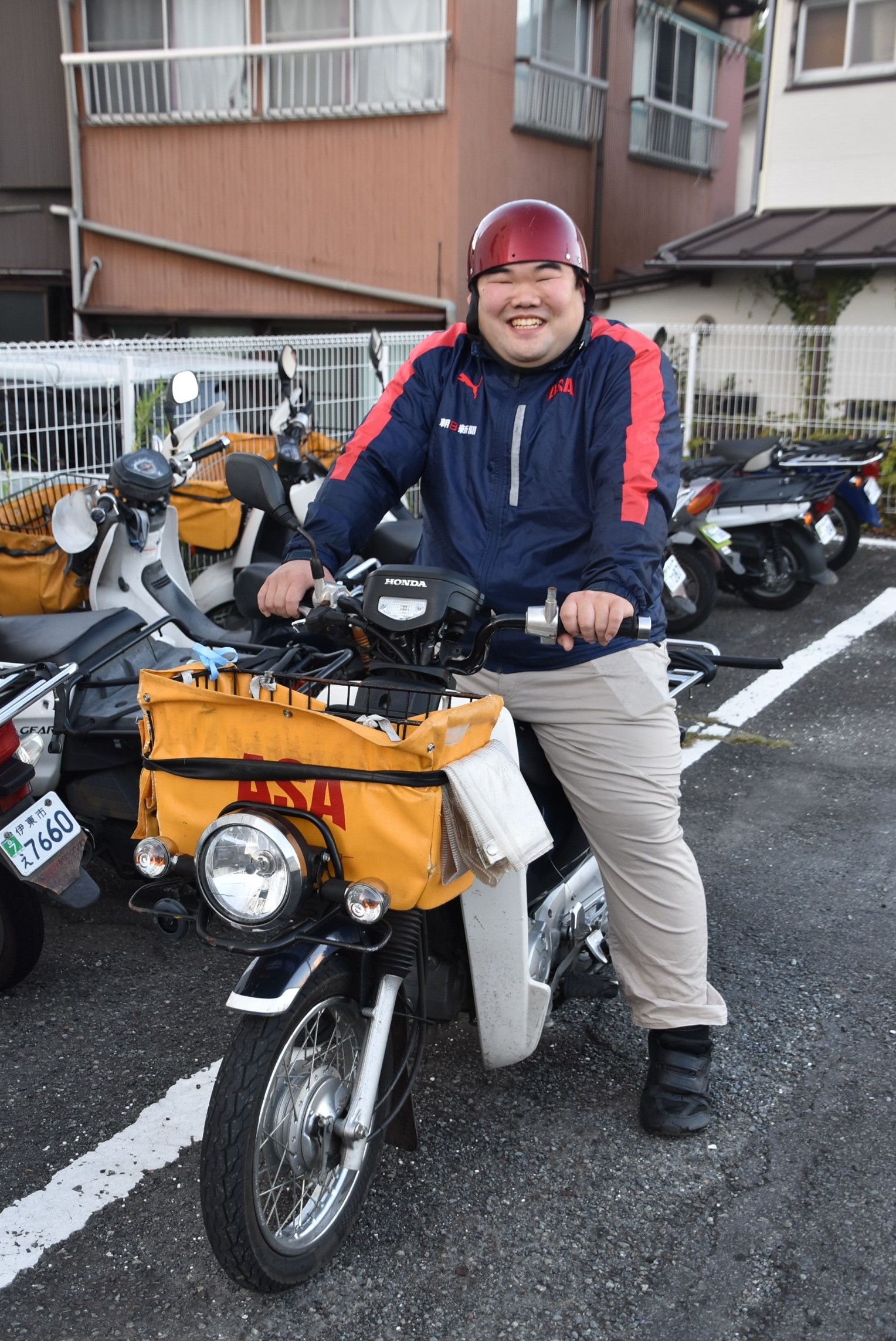 配達用のバイクにまたがる石井さん＝伊東市桜木町の星野新聞伊東店