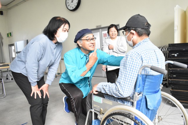 車椅子に乗った要支援者役の参加者と目線を合わせて会話する河合さん（左から２人目）＝三島市社会福祉会館
