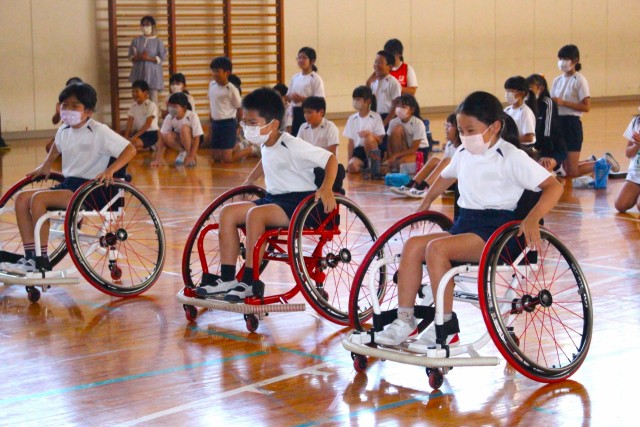 車椅子陸上競技について学びを深めた特別授業でバスケットボール用の車椅子を体験する児童＝熱海市の多賀小（１９日・写真の一部加工）