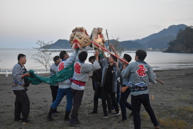 厄払いの願いを込めた「獅子のかみ合わせ」を行う若衆ら＝松崎町の松崎海岸