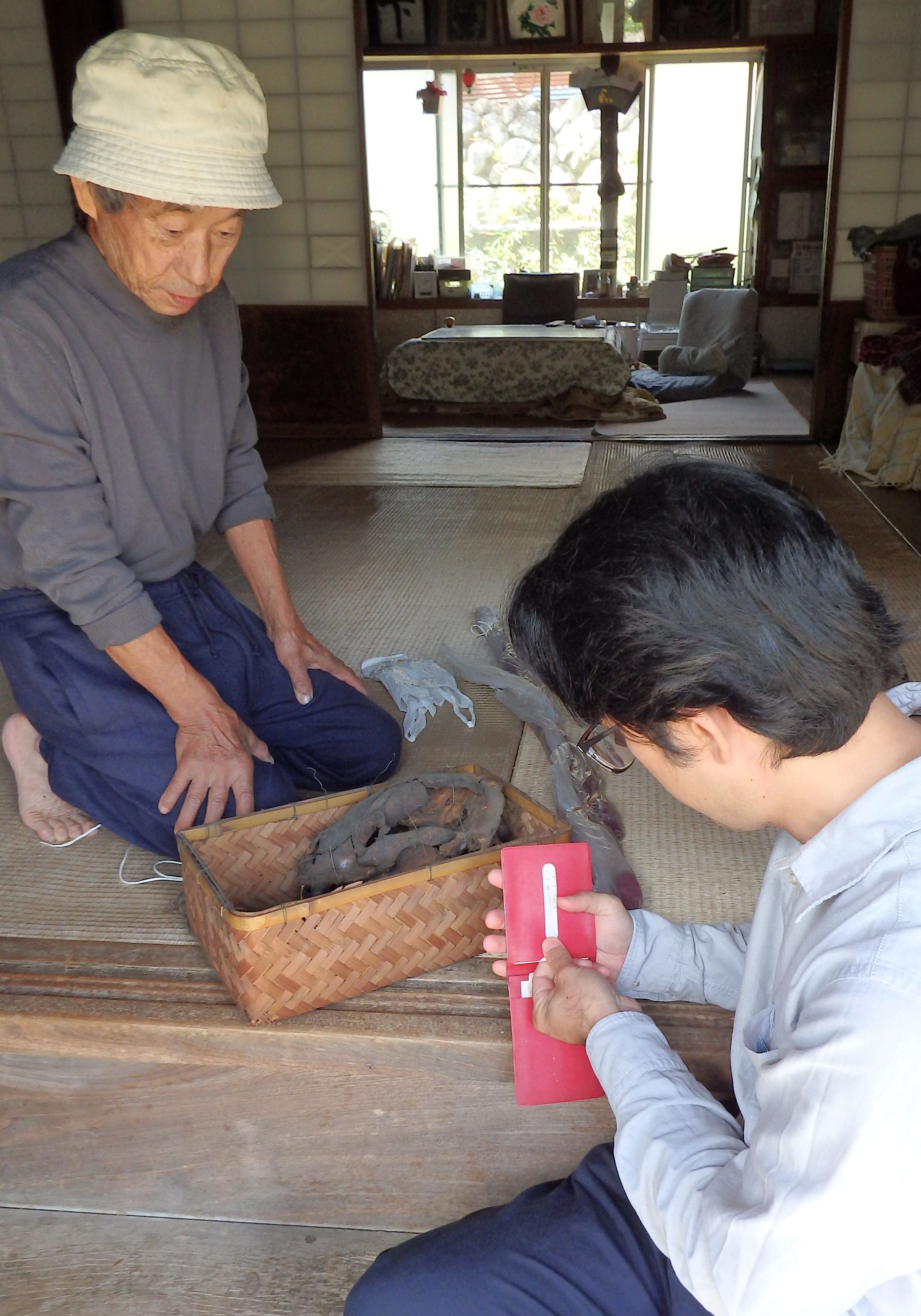 山本さん（写真左）宅を訪れ、クマの骨や仕留めた猟銃の寄贈手続きをする西岡さん＝松崎町池代