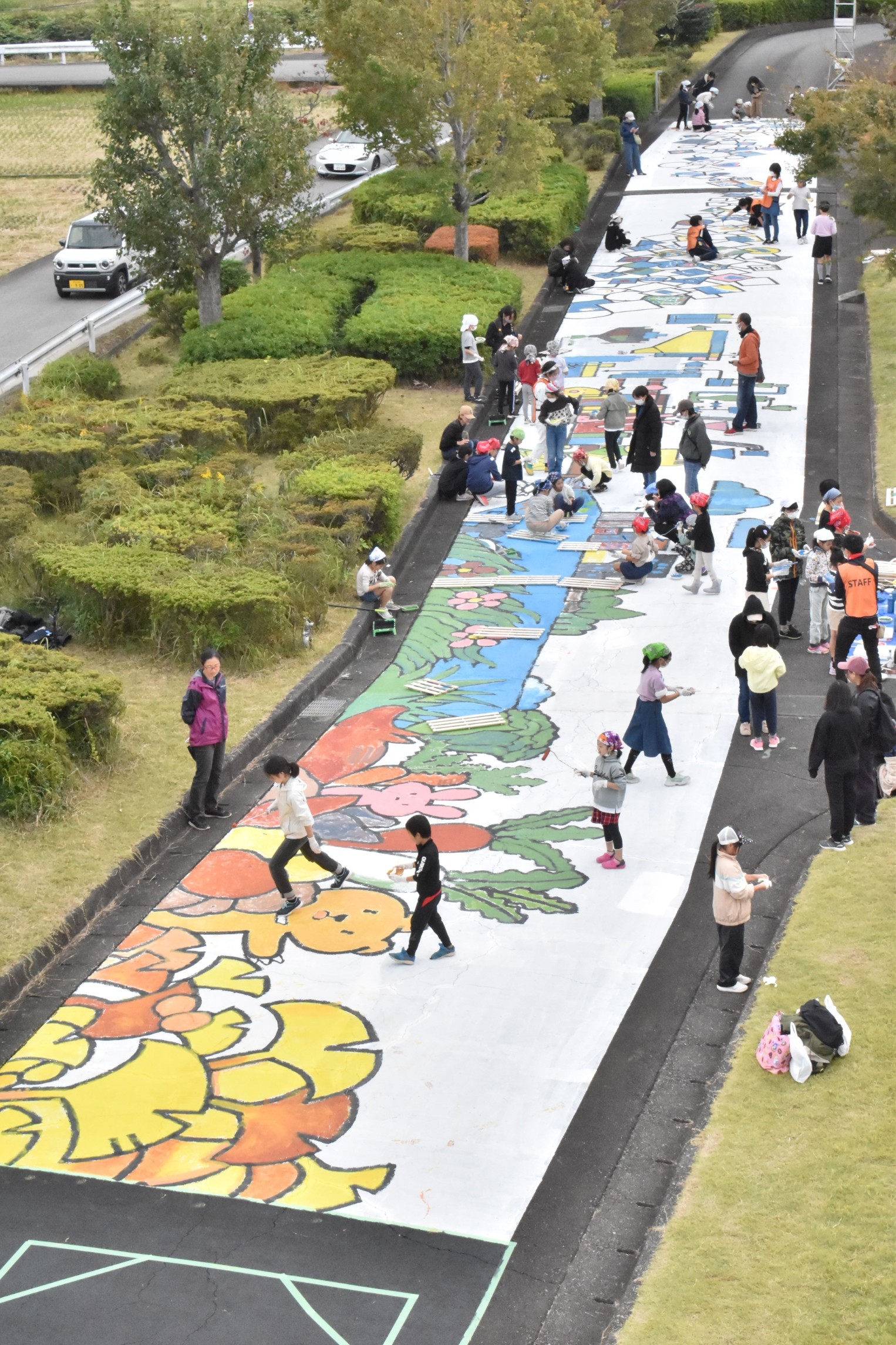 巨大な絵を道路に描く参加者＝三島市の浄化センター