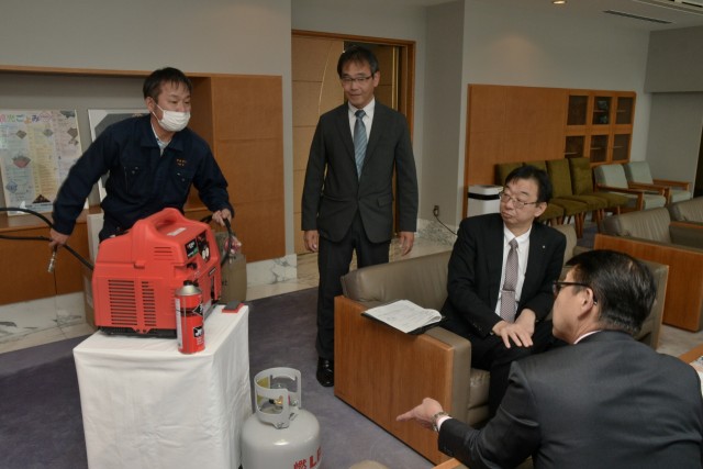 小野市長（右）にガス発電機の説明をする伊東ガス社員たち＝伊東市役所