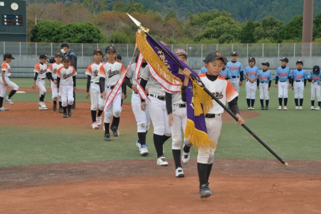 伊東ライオンズクラブ学童野球大会で、優勝旗を掲げてグラウンドを行進する南伊東ベアーズ・宇佐美少年野球団合同チームの選手たち＝伊東市のかどの球場（１２日）