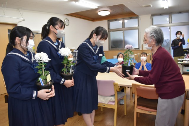 栽培した福助菊をデイサービス利用者に手渡す生徒＝河津町峰のデイサービス・バウム