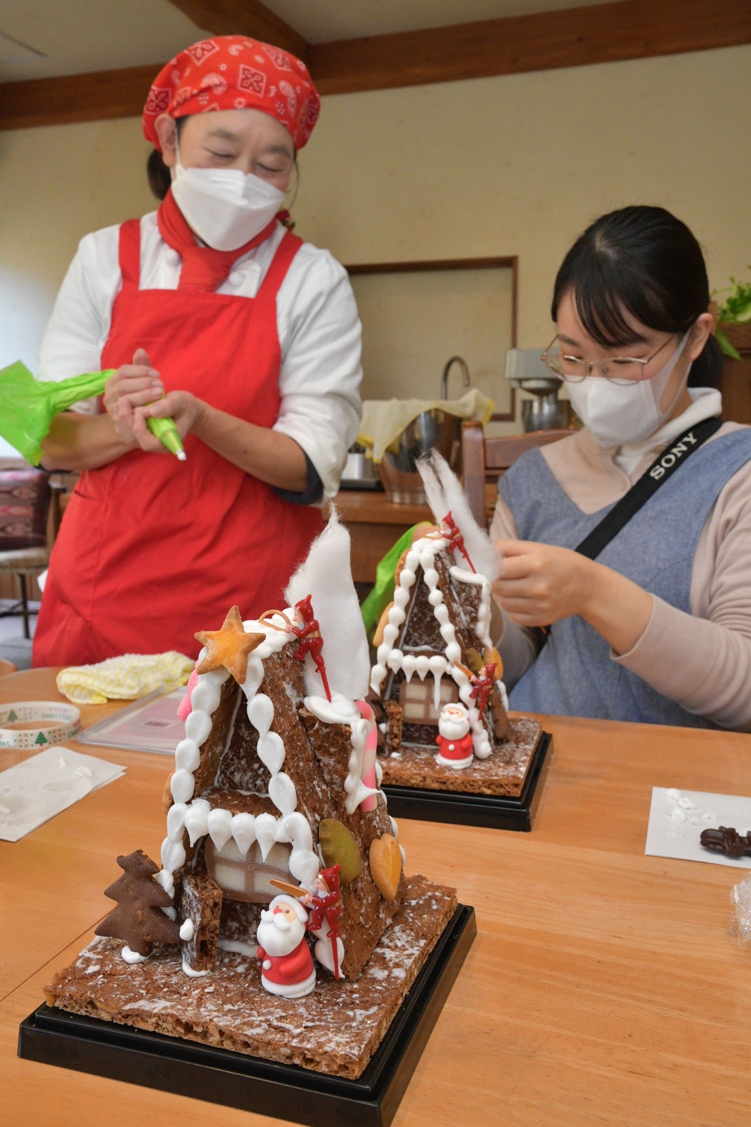 クリスマスに合わせたお菓子の家を作る体験教室で、西伊豆町の製菓店「秋月」の須田睦さん（左）の指導を受ける参加者＝伊東市池のグランベール伊豆（２６日）