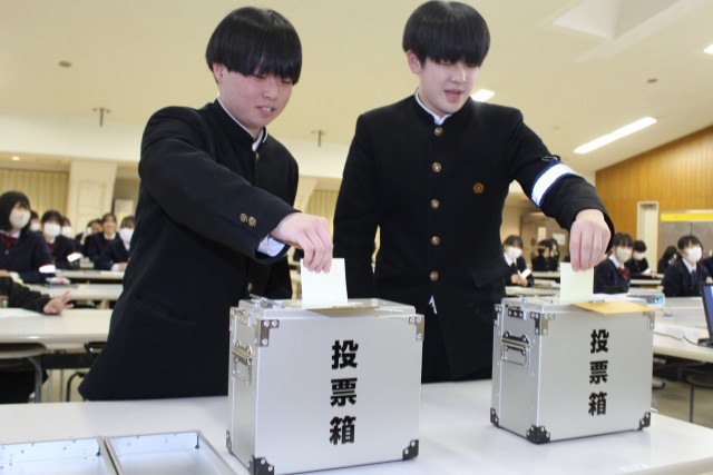 実際に使われている投票箱に模擬投票用紙を入れる生徒＝熱海市の多賀中