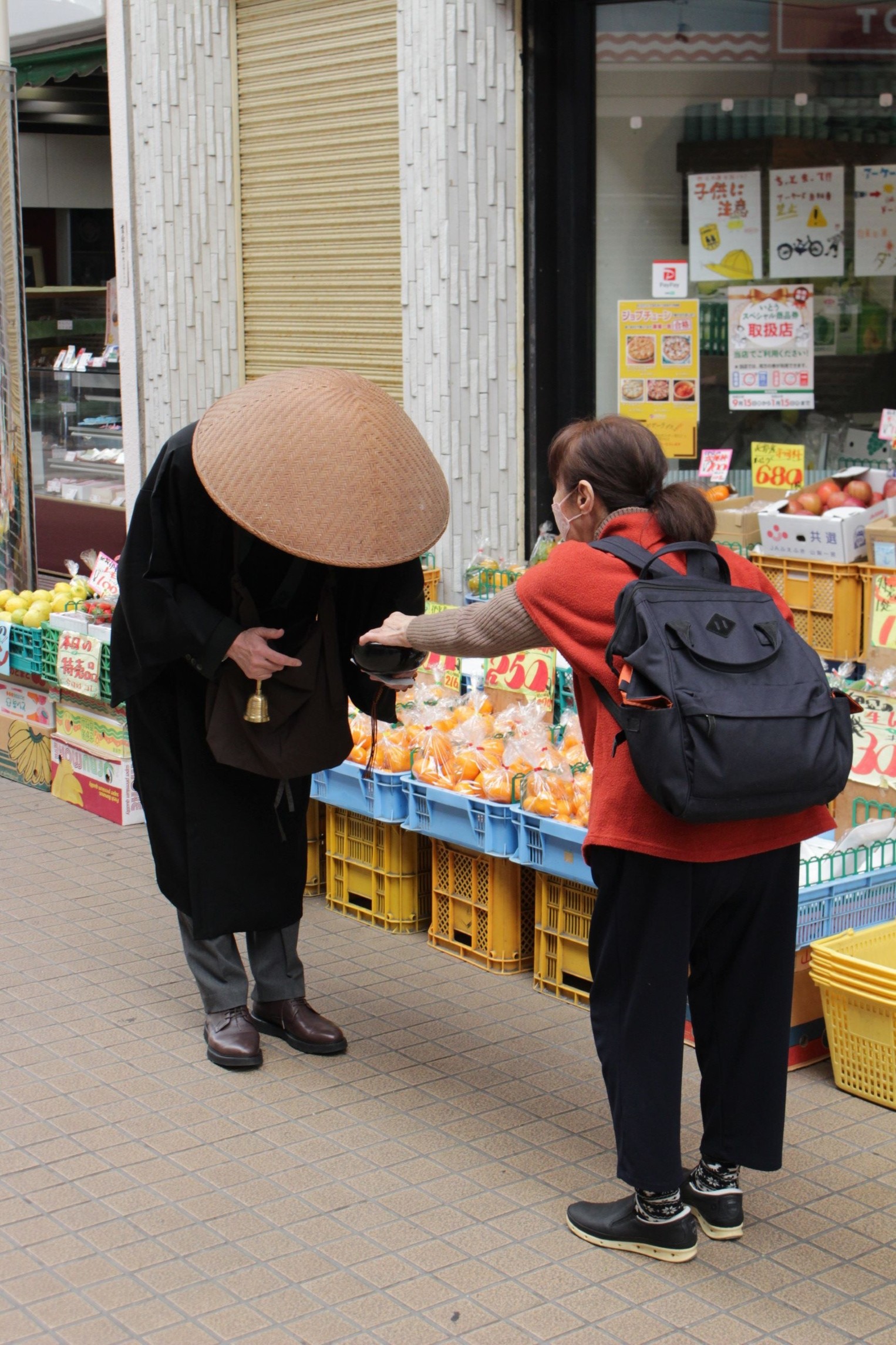 歳末助け合い托鉢で市民からの善意を受け取る僧侶＝伊東市のキネマ通り