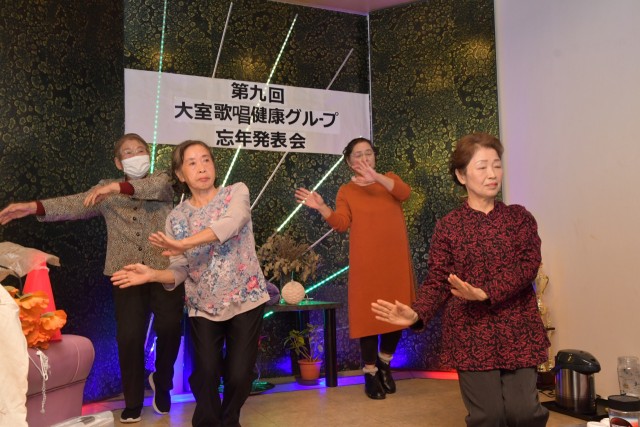 大室歌唱健康グループの忘年発表会で「人生百歳花咲かそう」に合わせて踊るメンバー＝伊東市竹の内のスナックユニコーン（１４日）