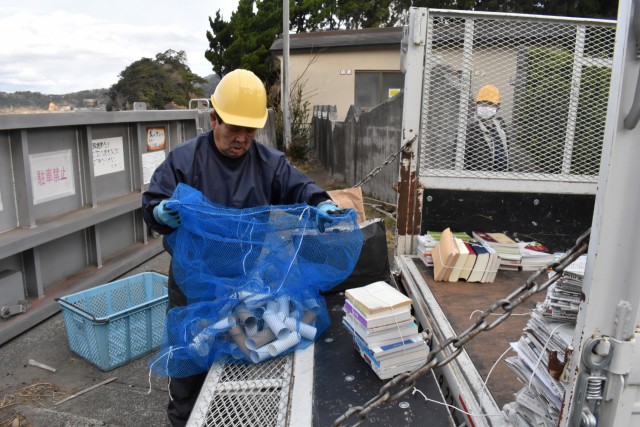 トイレットペーパーの芯などの雑がみを回収する職員＝松崎町の松崎海岸