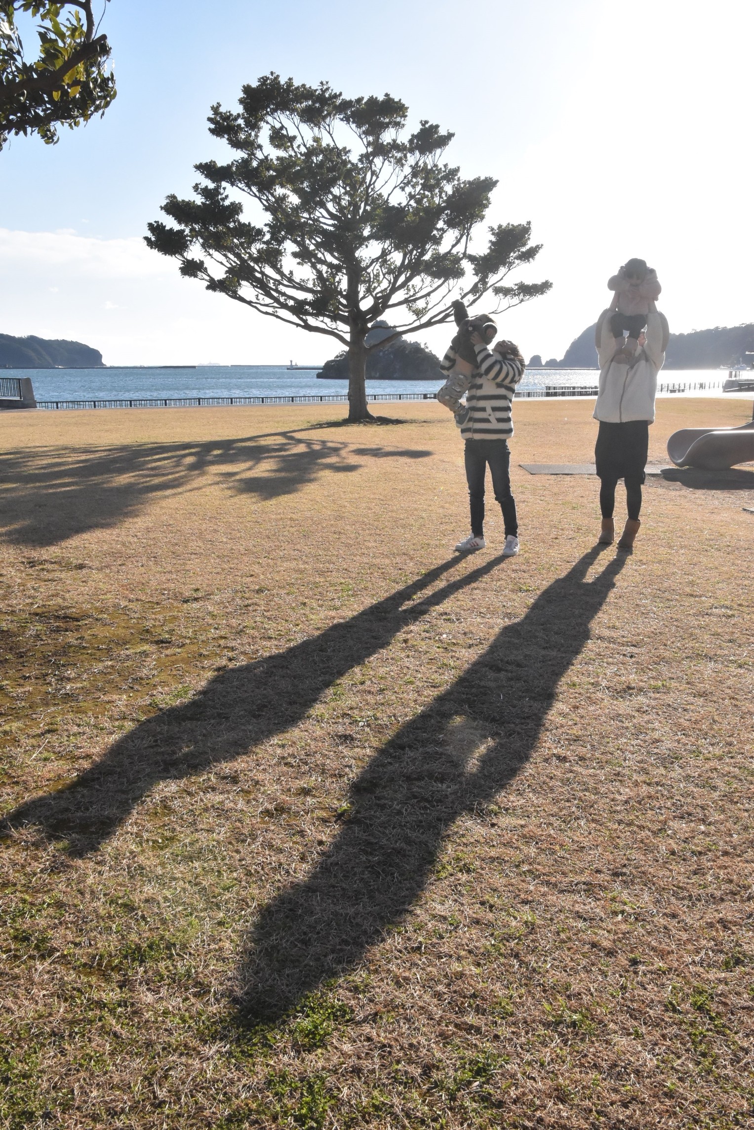 長い影で遊ぶ親子＝下田市柿崎のまどが浜海遊公園
