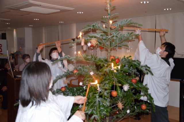 クリスマスツリーのろうそくに火をともす職員＝伊東市八幡野の伊豆高原十字の園