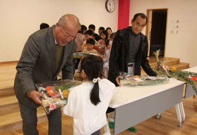 園児にお飾りを手渡す宮本理事長（左）ら＝伊豆市の修善寺東こども園