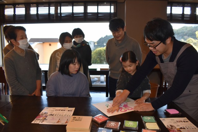 小池丸さん（右）の手ほどきを受け手形アートを楽しむ参加者＝東伊豆町の熱川プリンスホテル