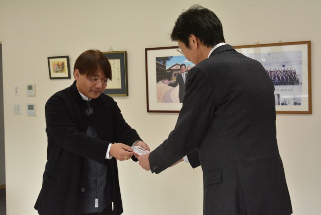 斉藤市長（右）に支援金を手渡す坂本さん＝熱海市役所