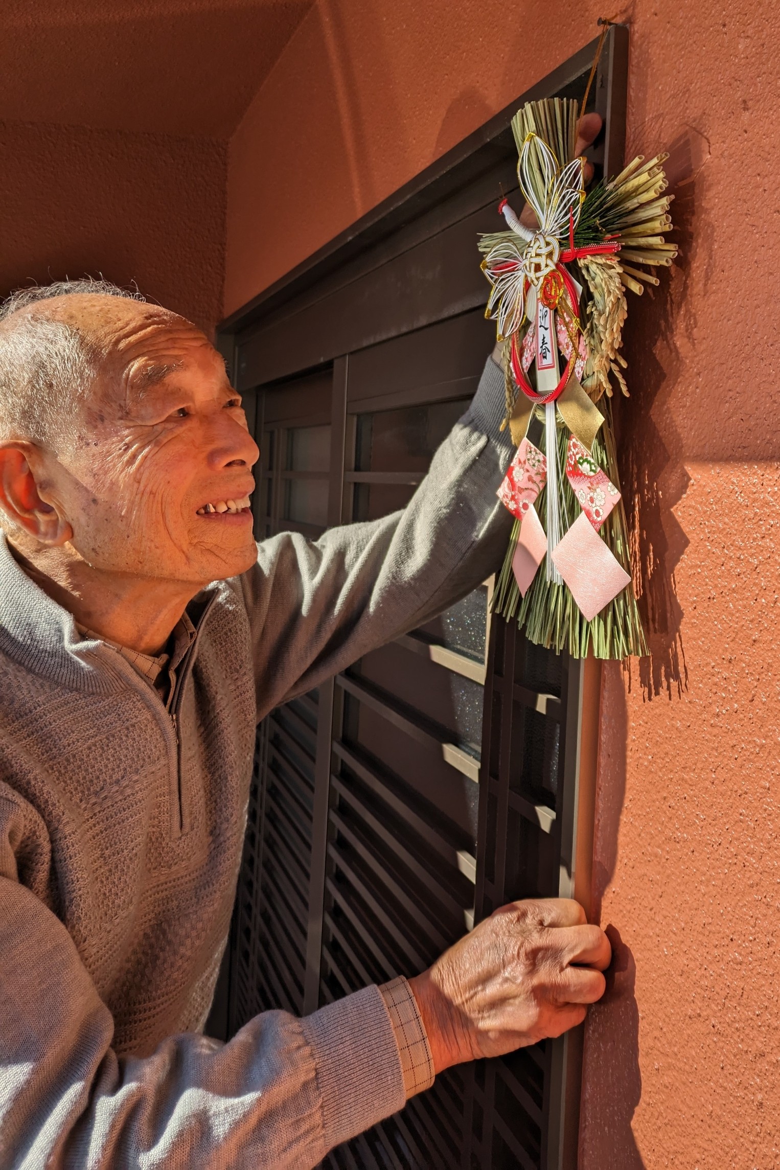 ３年ぶりとなる自宅での正月に向け、玄関にお飾りを取り付ける小松さん＝熱海市伊豆山