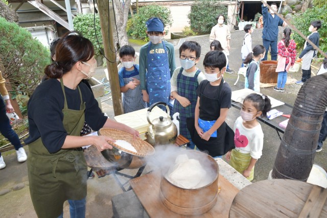 宝専寺の餅つきイベントでかまどを使いもち米を蒸す参加者たち＝伊東市新井（１６日）